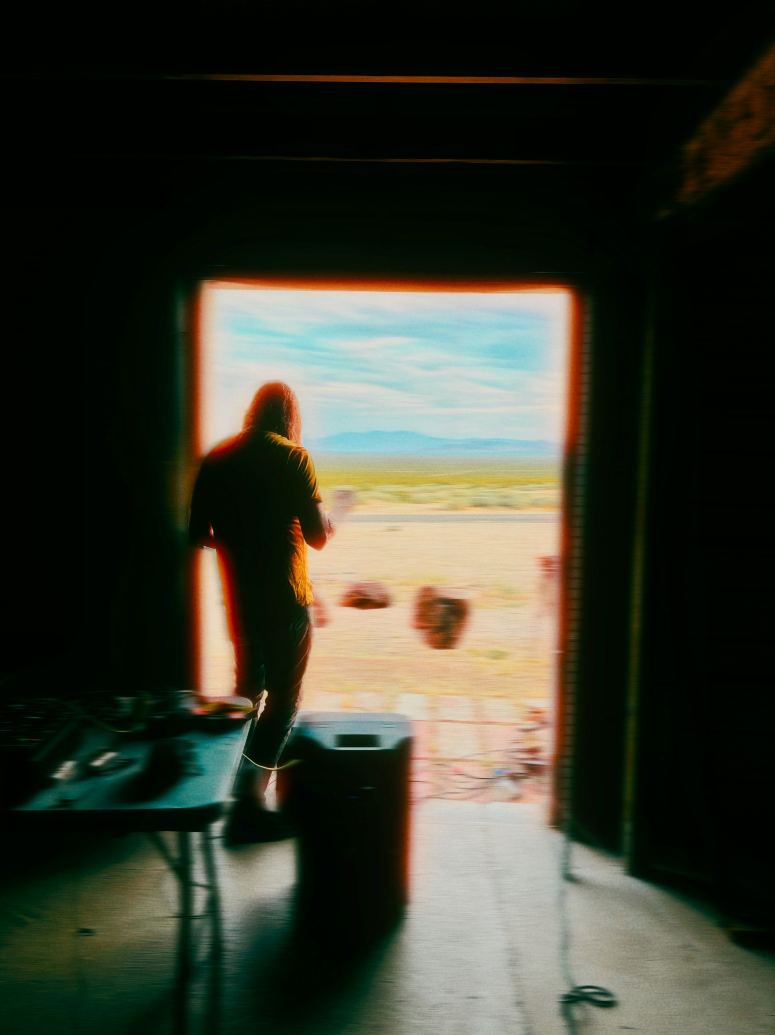 Daniel Menche inside the Red Barn Arts Center in Rhyolite, Nevada, standing near the open doorway during his residency.
